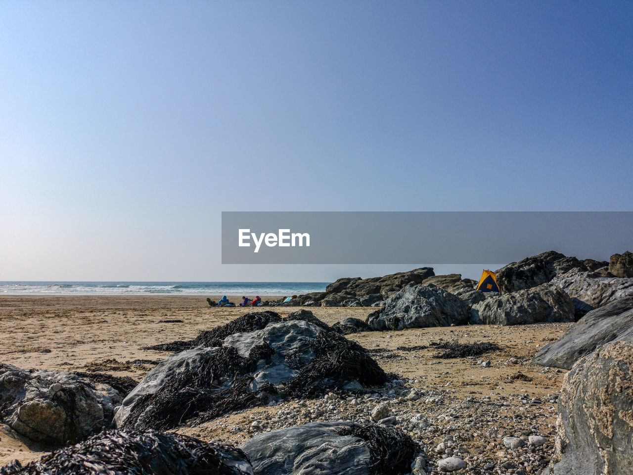 ROCKS ON BEACH AGAINST CLEAR SKY