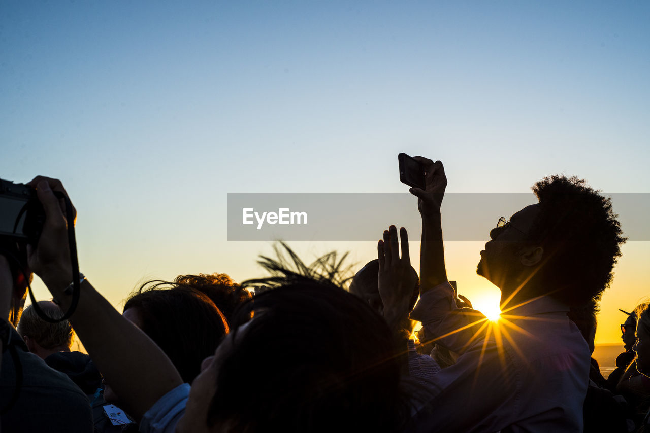 People photographing against sky during sunset