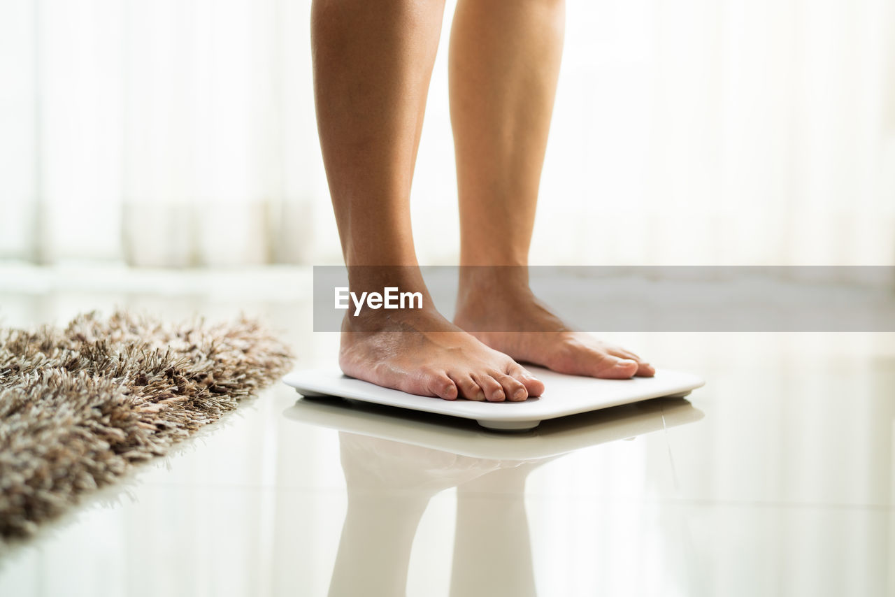 Young woman standing on digital weight scale