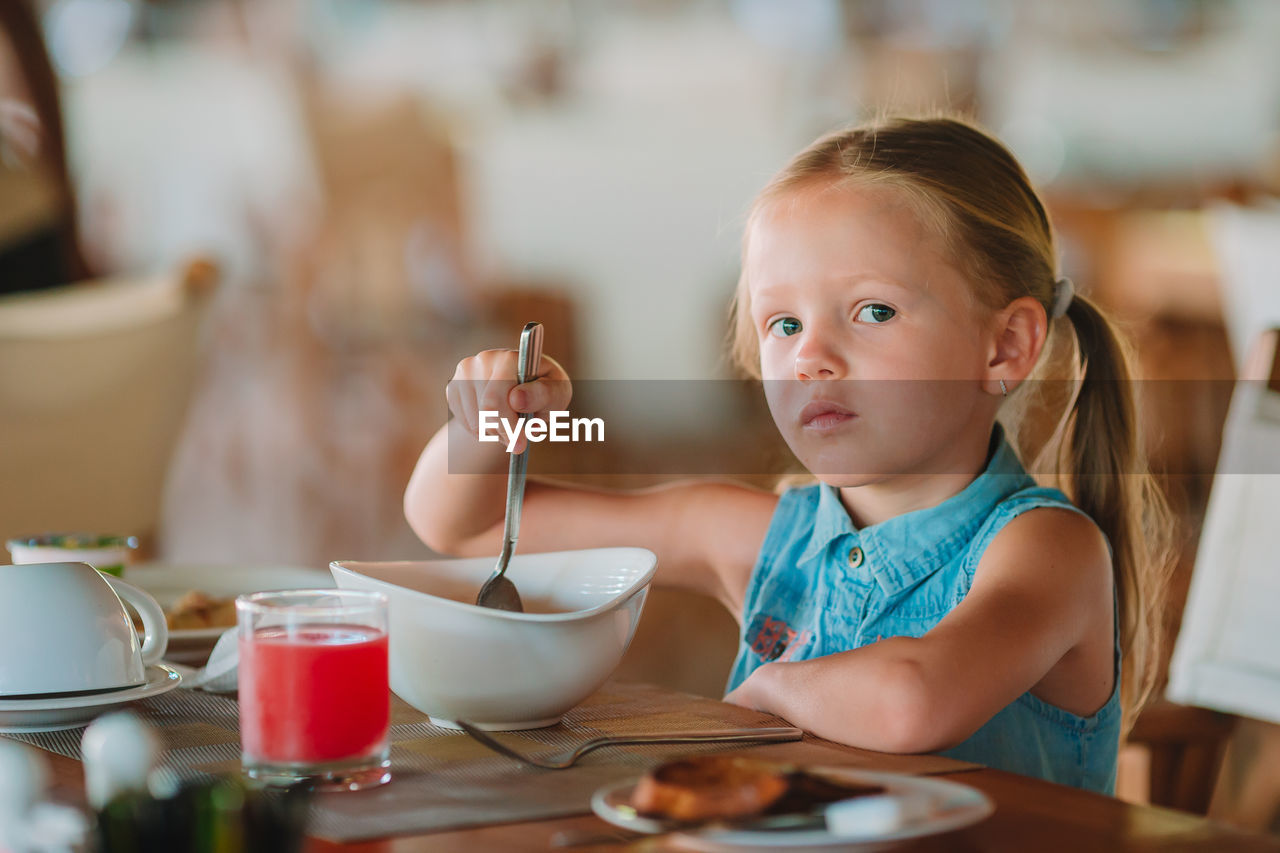 Portrait of cute girl eating breakfast at home