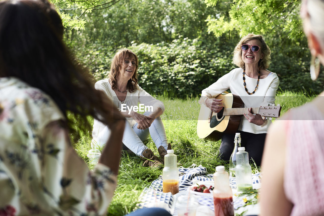 Group of women with guitar having fun at a picnic in park