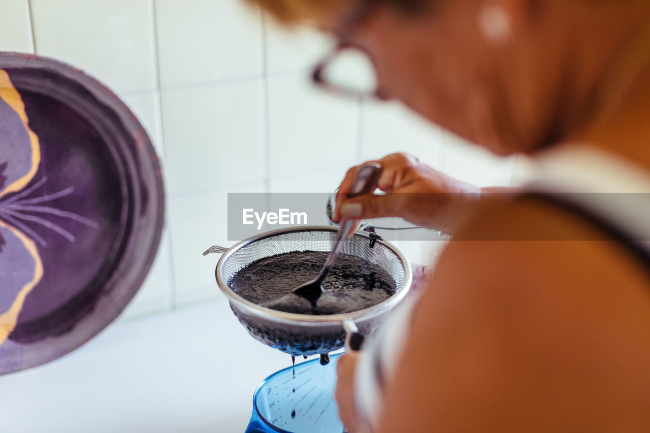 Close-up midsection of woman preparing juice in kitchen