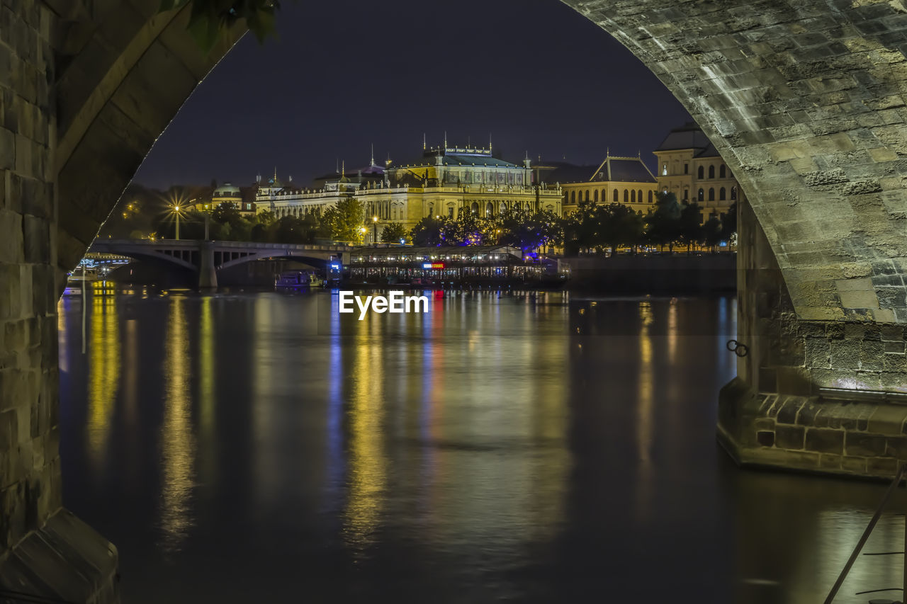 ILLUMINATED BRIDGE OVER RIVER AGAINST SKY