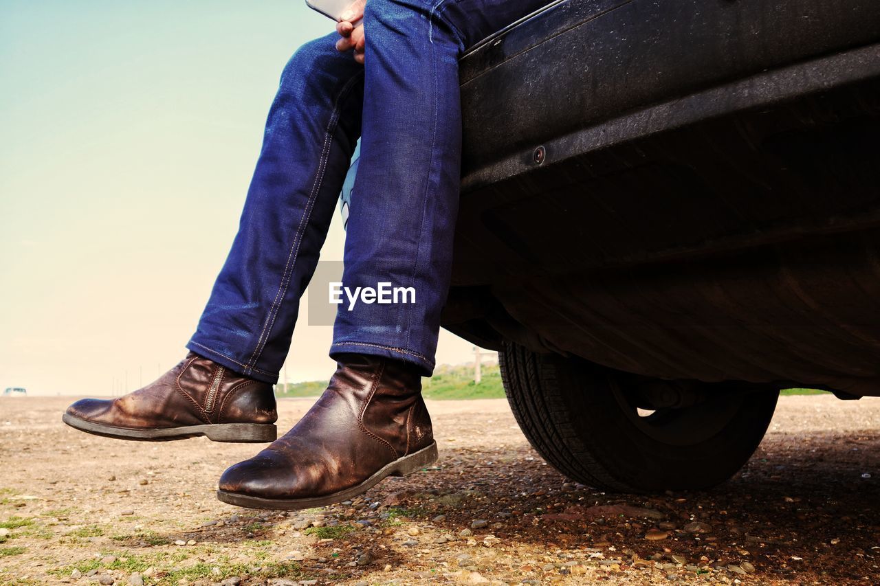 Low section of man sitting on car