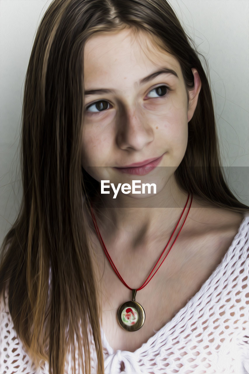 Close-up of thoughtful young woman looking away while standing against wall