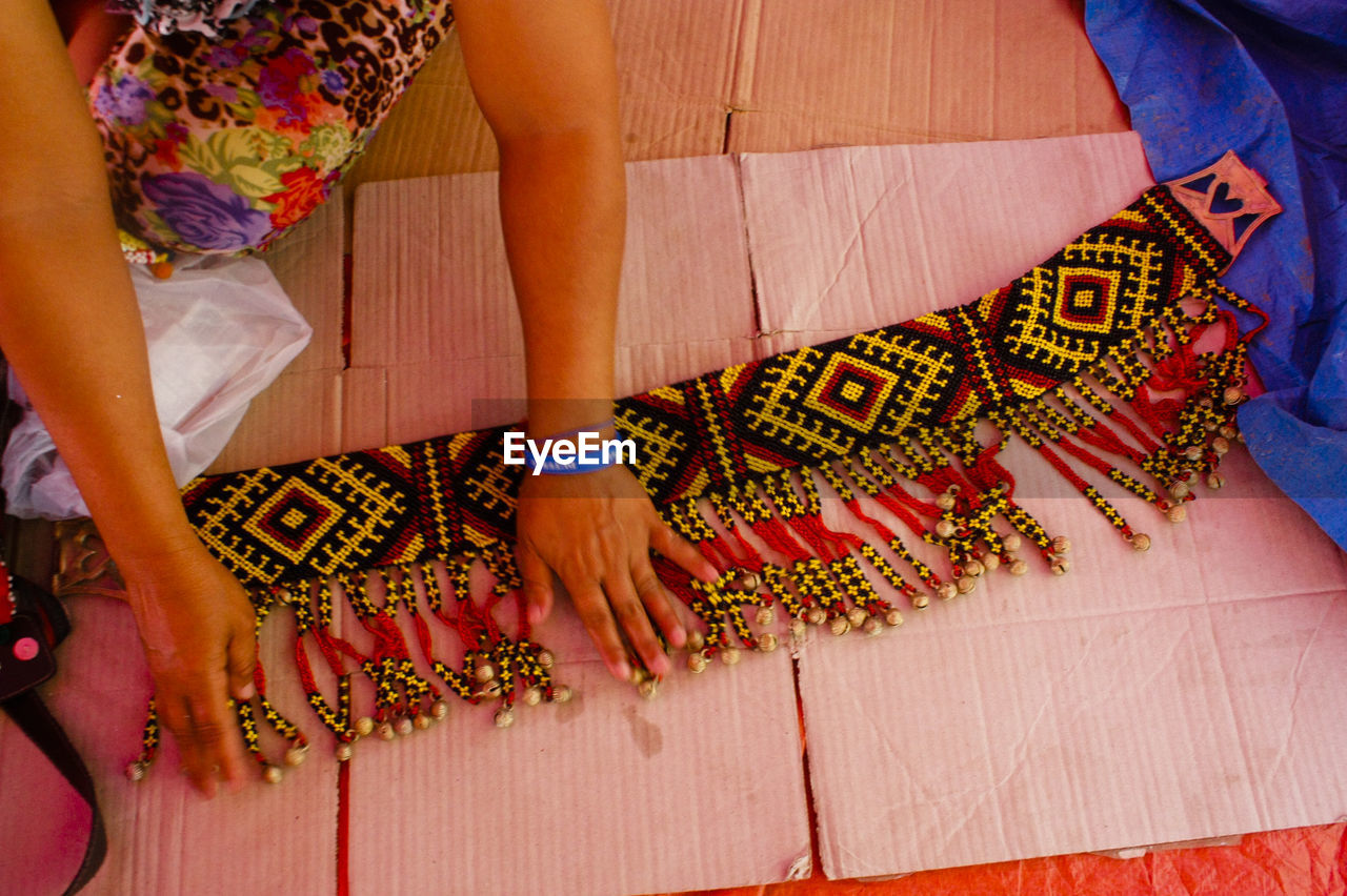 Cropped hands of woman touching beaded fabric