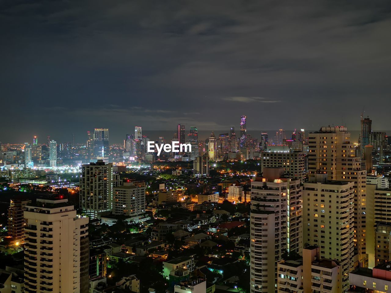 Illuminated modern buildings in city against sky