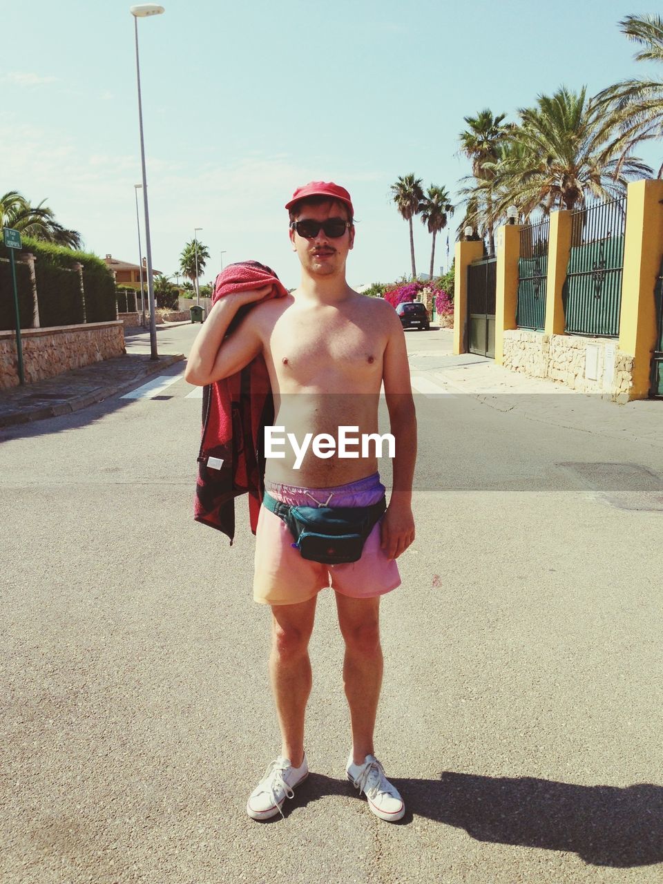 Full length portrait of shirtless man holding towel while standing on road