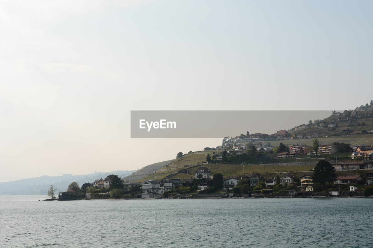 Scenic view of sea by buildings against clear sky