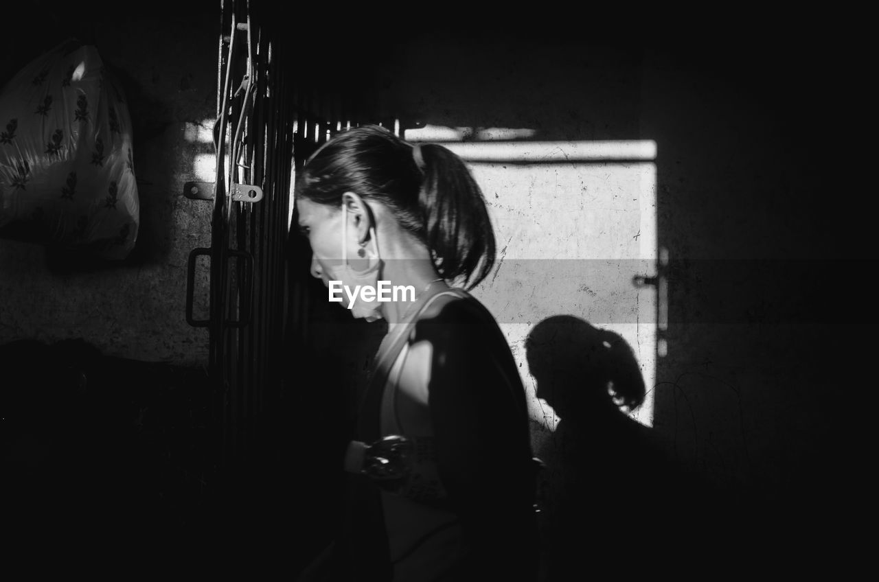 Side view of woman standing against wall