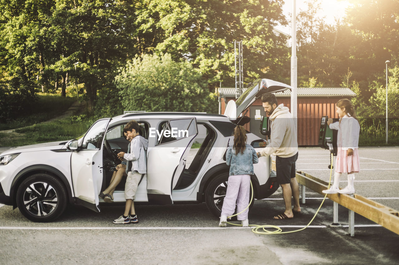 Family charging electric car at station