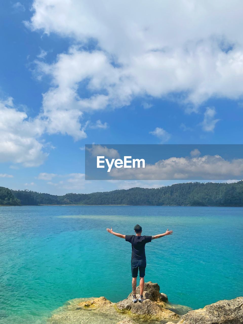 water, sea, arm, one person, limb, sky, nature, human limb, arms outstretched, cloud, beauty in nature, vacation, holiday, full length, trip, scenics - nature, arms raised, leisure activity, blue, adult, standing, ocean, mountain, land, shore, rear view, body of water, tranquility, day, beach, rock, men, idyllic, travel, lifestyles, tranquil scene, relaxation, bay, horizon, outdoors, travel destinations, young adult, coast, environment, casual clothing, adventure, non-urban scene, summer, turquoise colored, tourism, copy space, person, enjoyment, sports