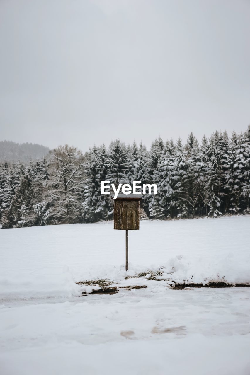 Mailbox amidst snow covered field against sky