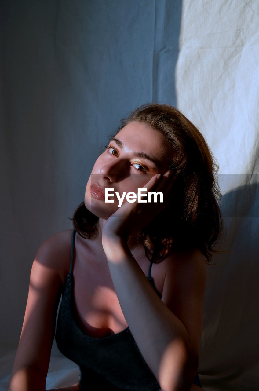 Portrait of young woman looking away against black background