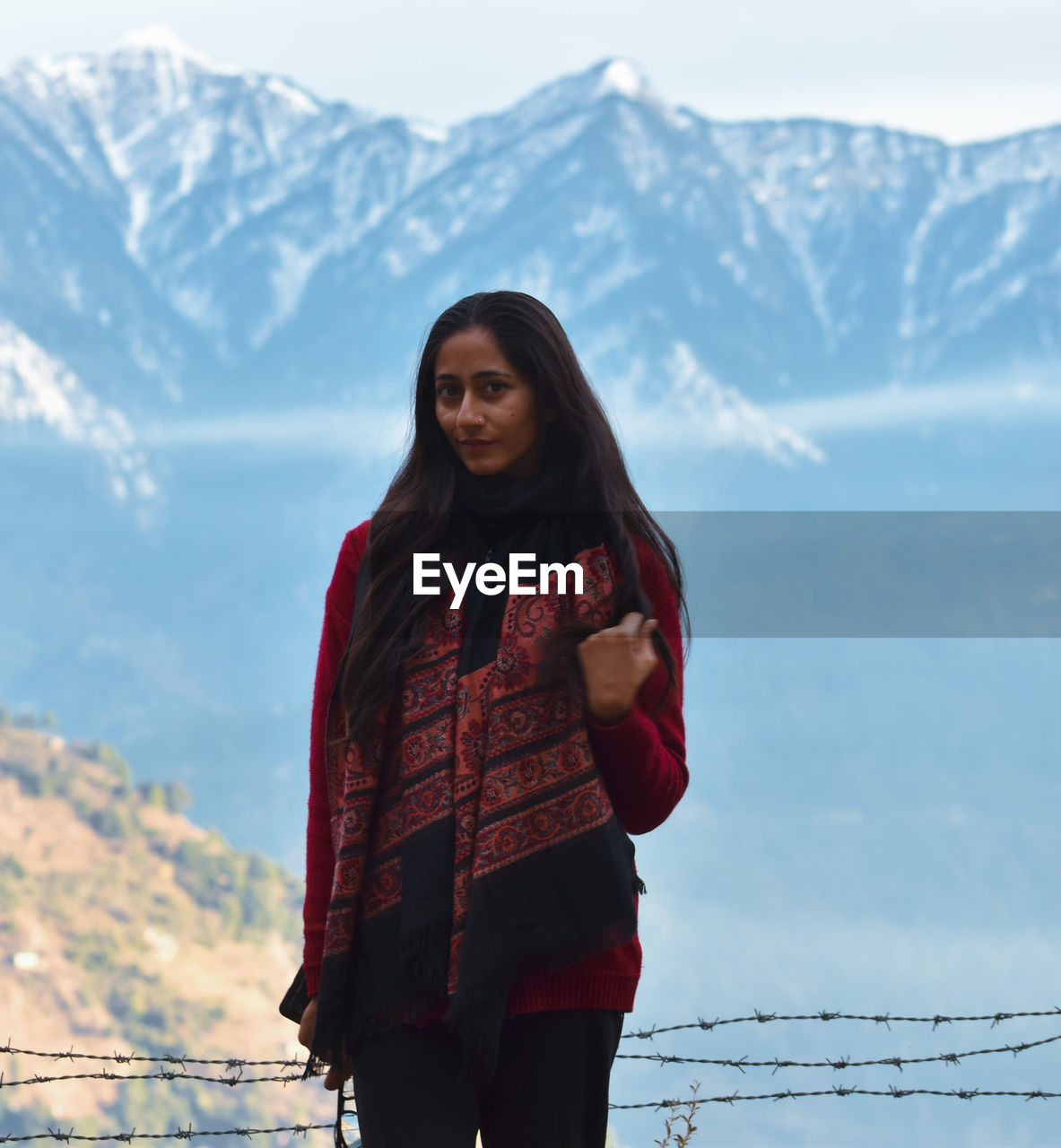 Portrait of beautiful young woman standing on snow against sky