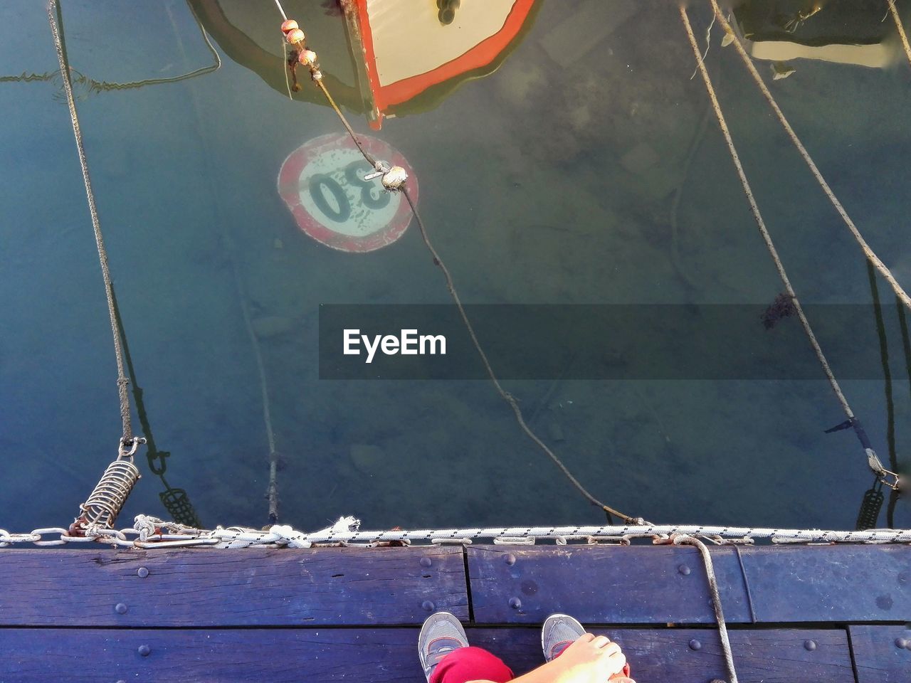 Low section of man standing on pier over sea