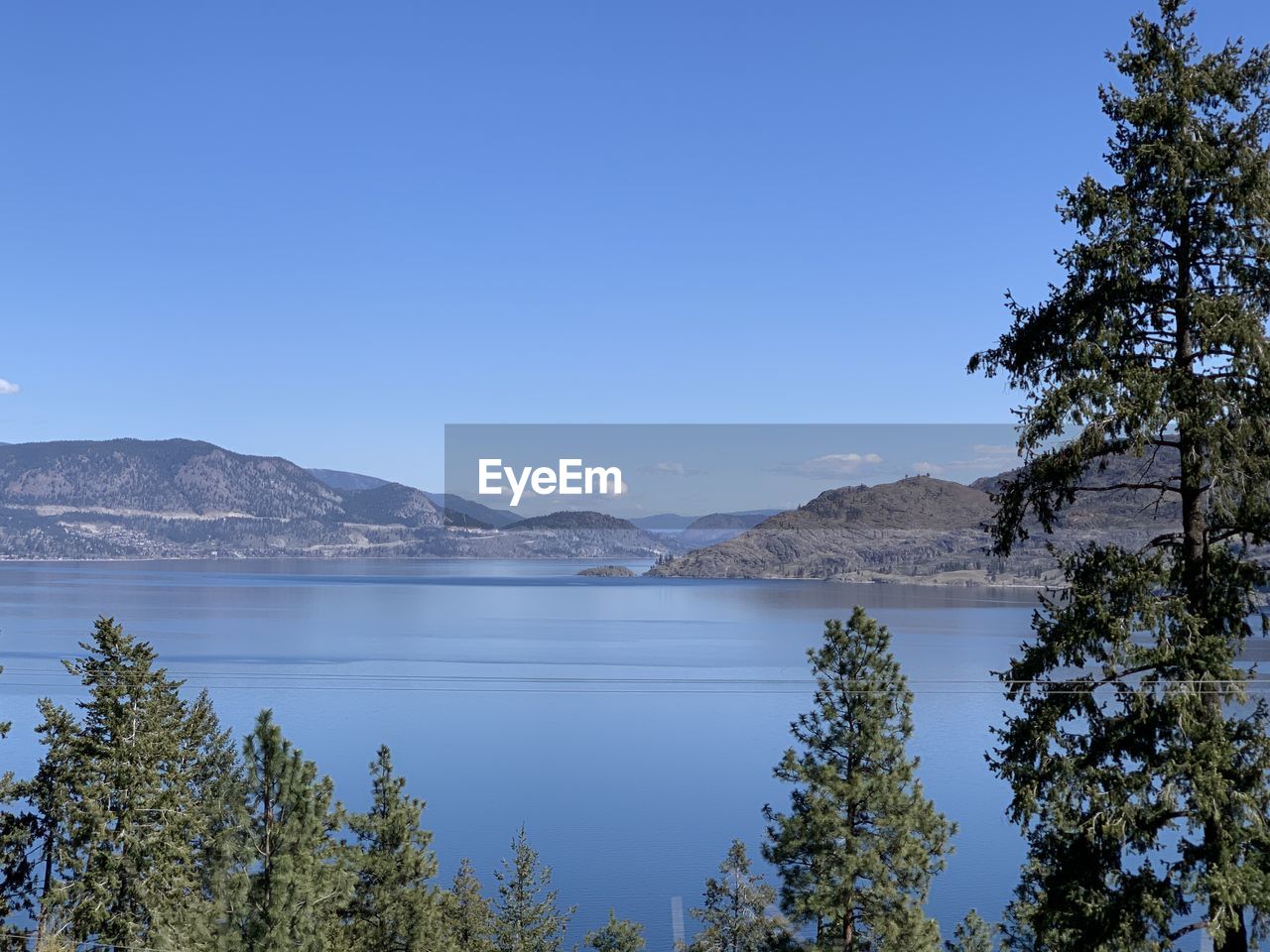 Scenic view of lake and mountains against clear blue sky