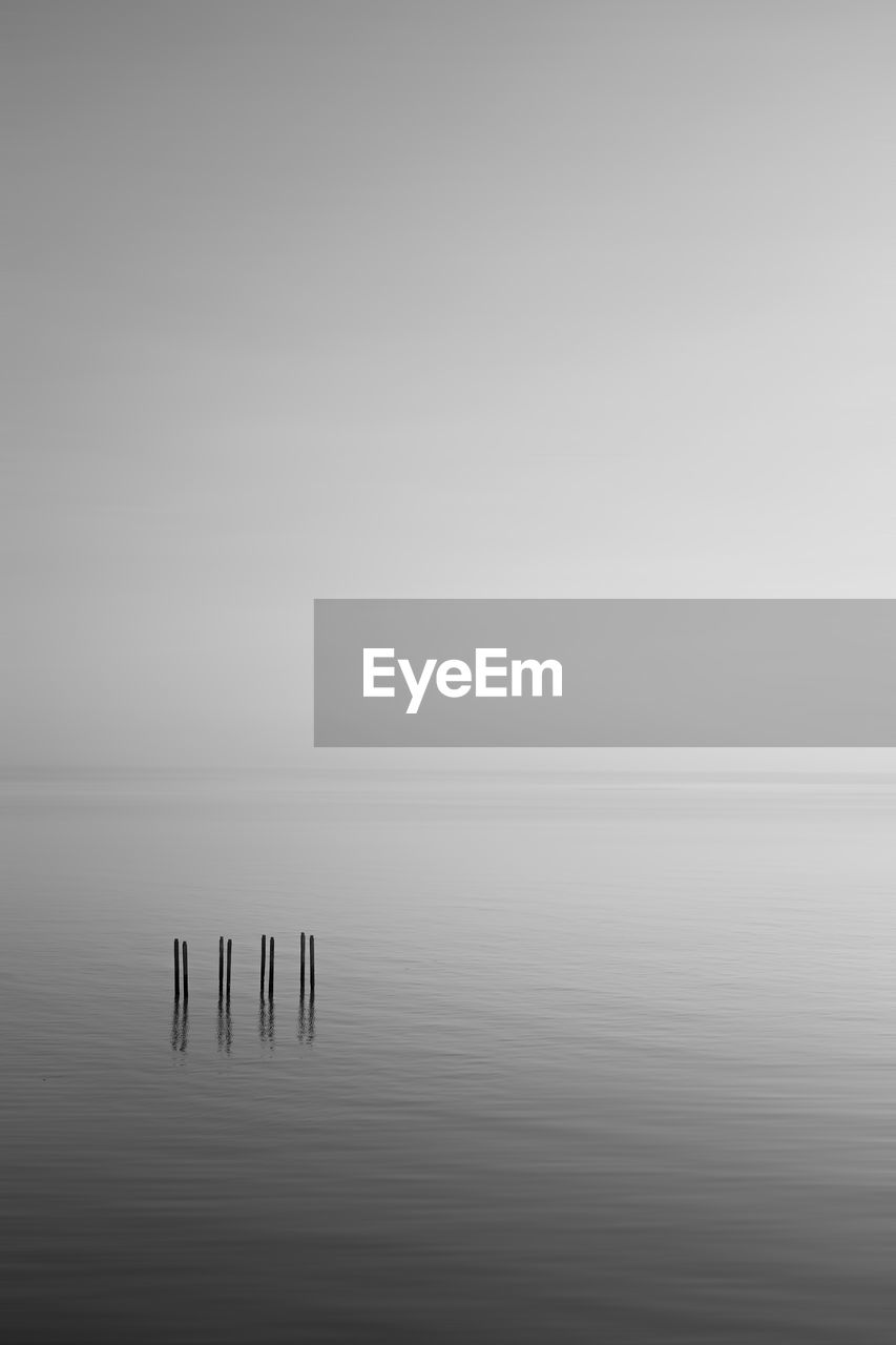 WOODEN POST IN SEA AGAINST SKY