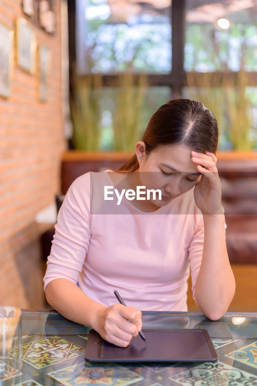 YOUNG WOMAN USING PHONE ON TABLE