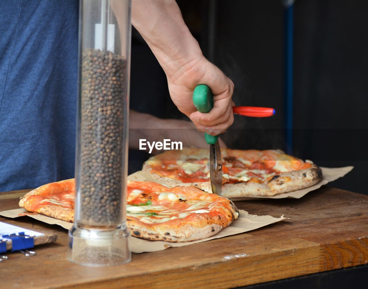 Midsection of man cutting pizza