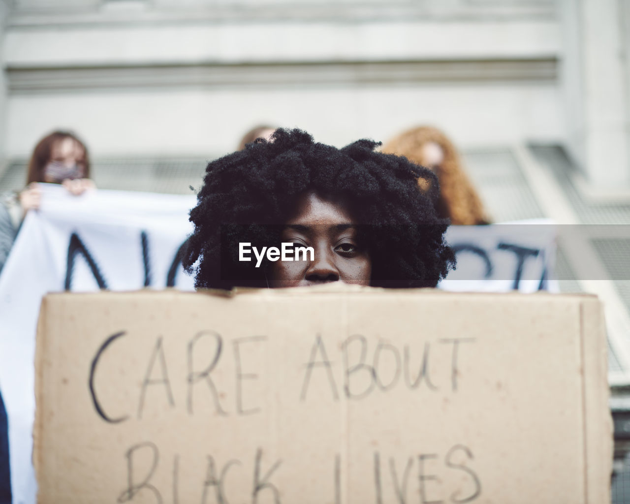 PORTRAIT OF YOUNG WOMAN WITH TEXT ON SIGN