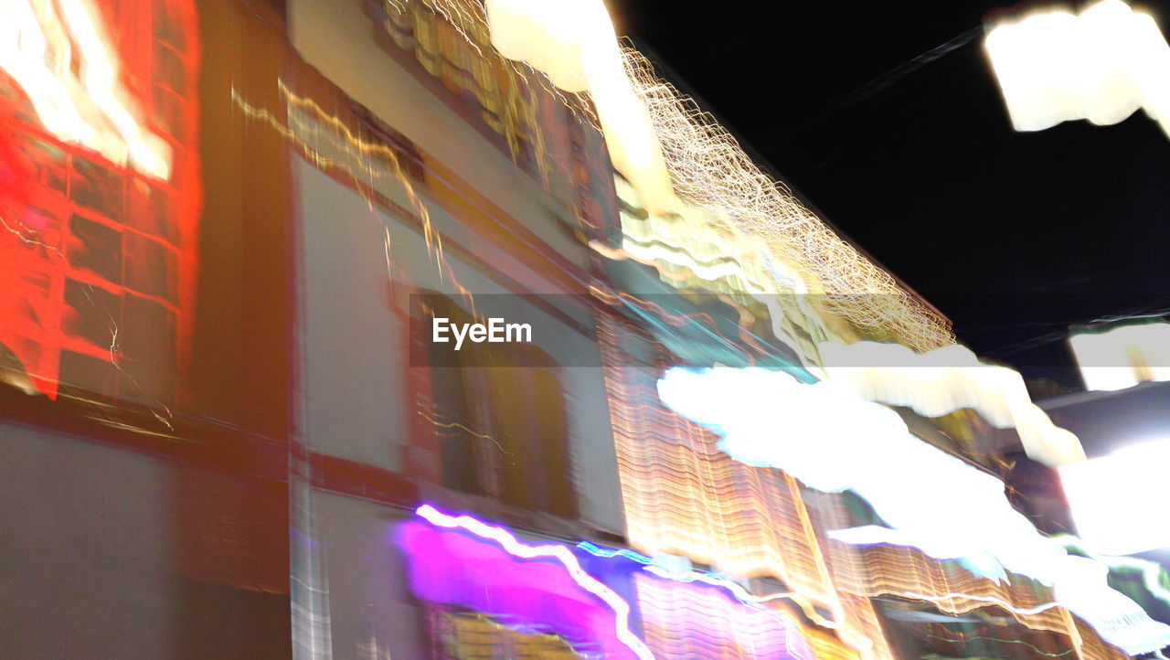 Low angle view of light trails against building at night