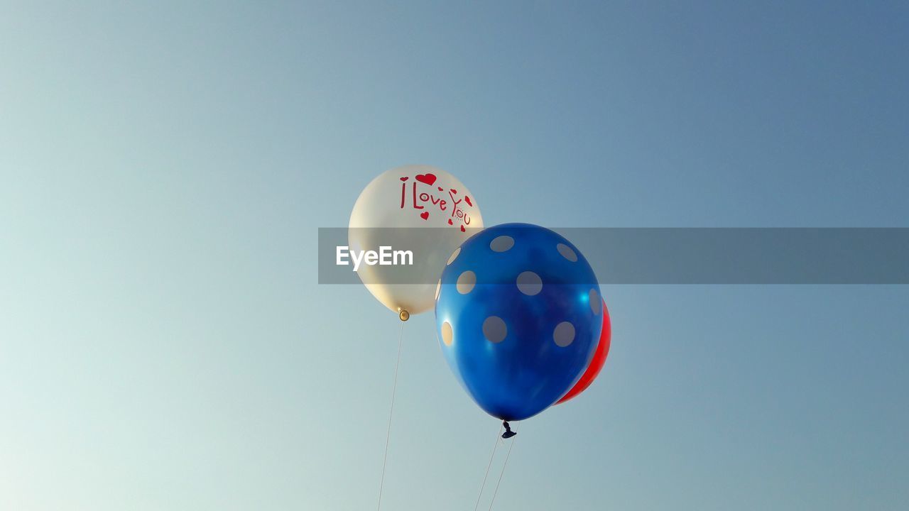 Low angle view of balloons against blue sky