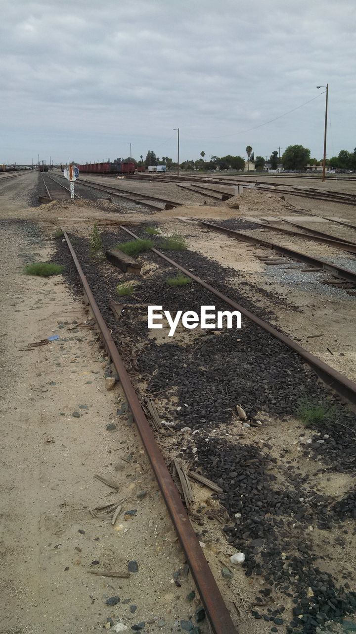 Surface level of railroad track against cloudy sky