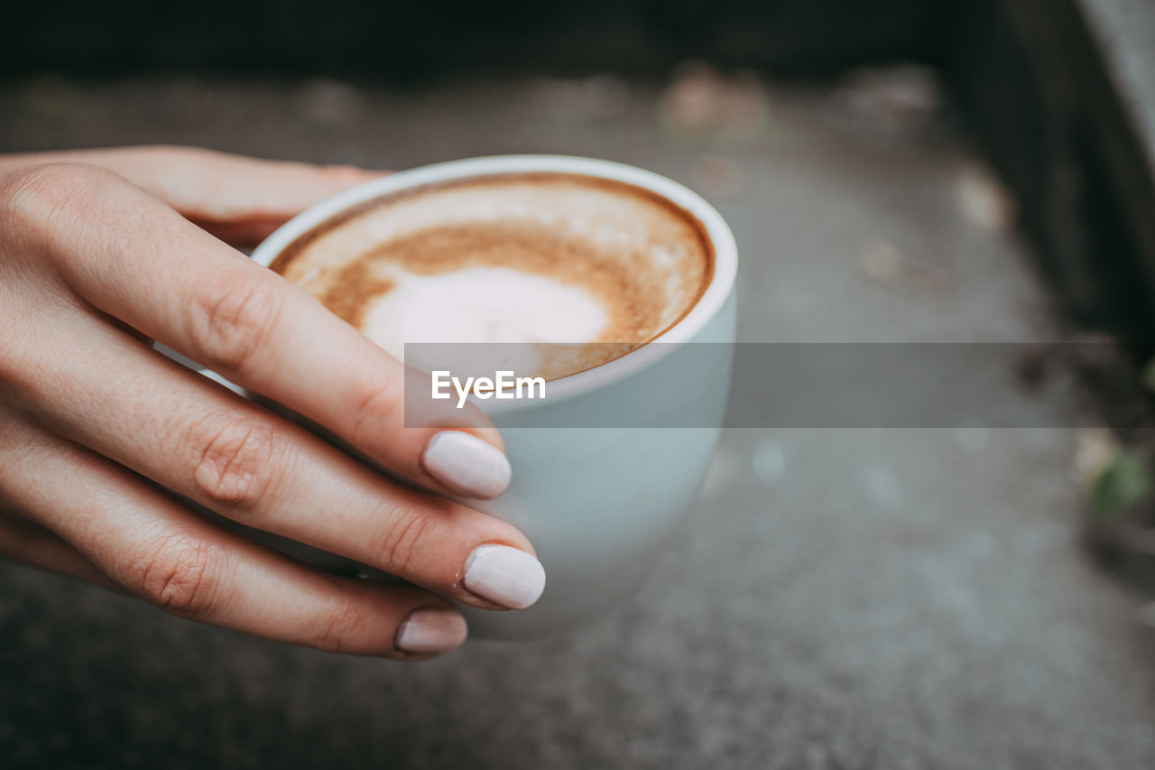 CLOSE-UP OF HAND HOLDING COFFEE