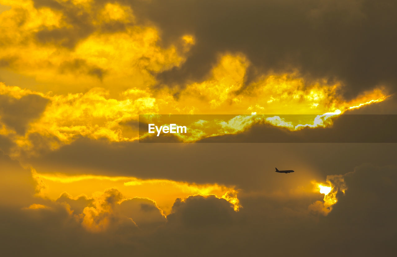 Low angle view of silhouette airplane against sky at sunset