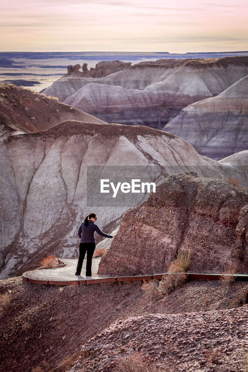 Woman standing on footpath against rock formation