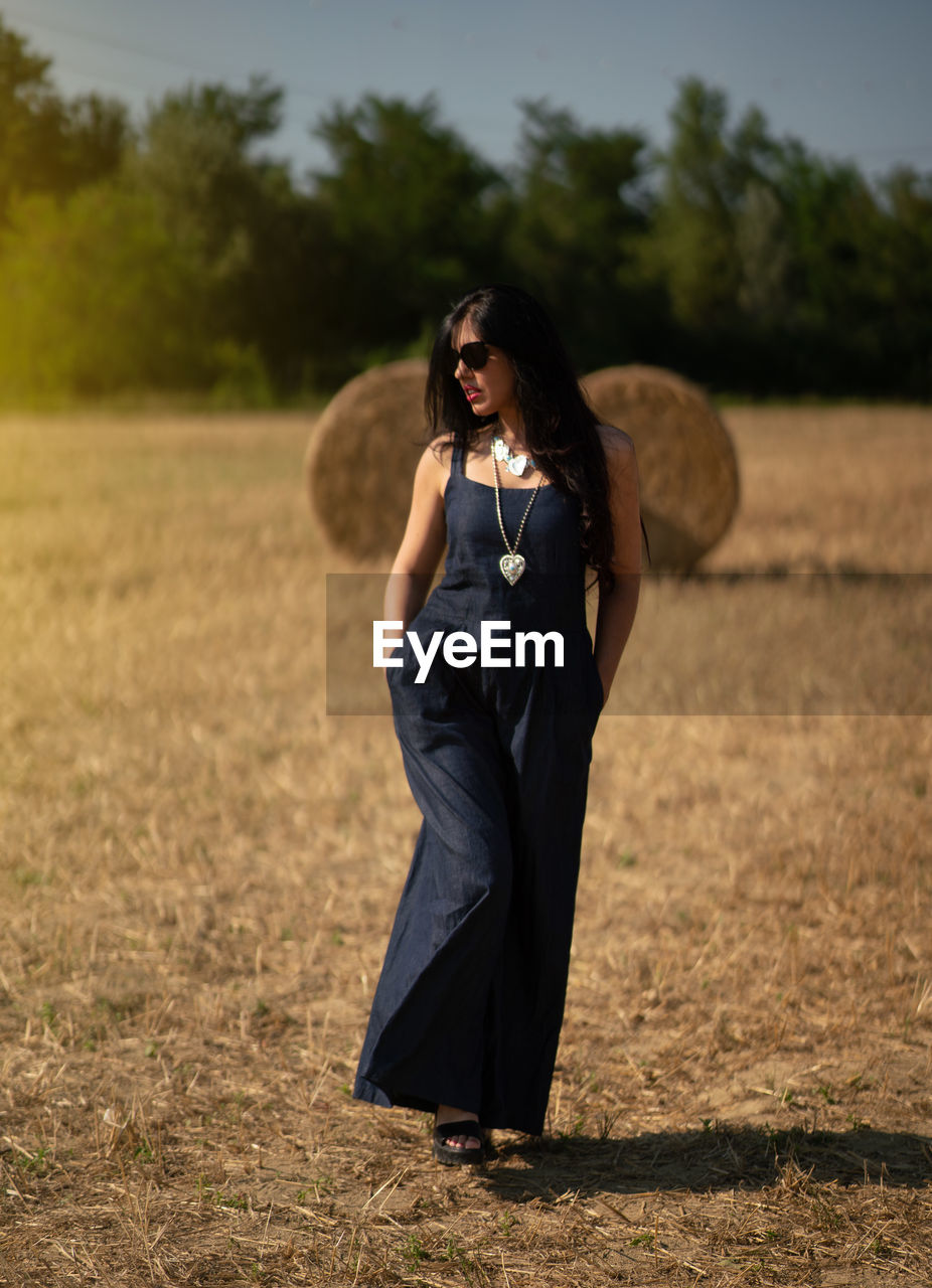 PORTRAIT OF YOUNG WOMAN STANDING ON LAND