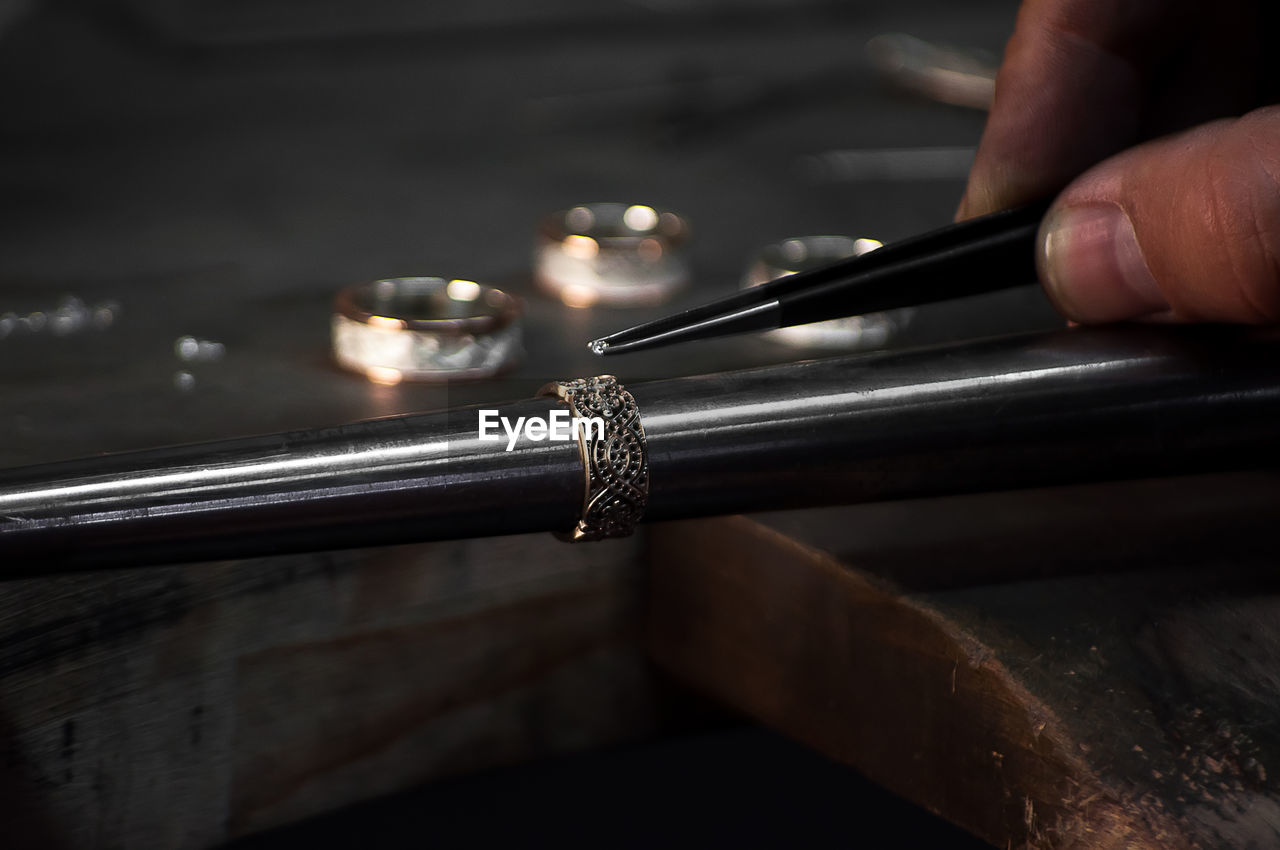 Close-up of hand of a goldsmith setting the diamond on the ring. craft jewelery 