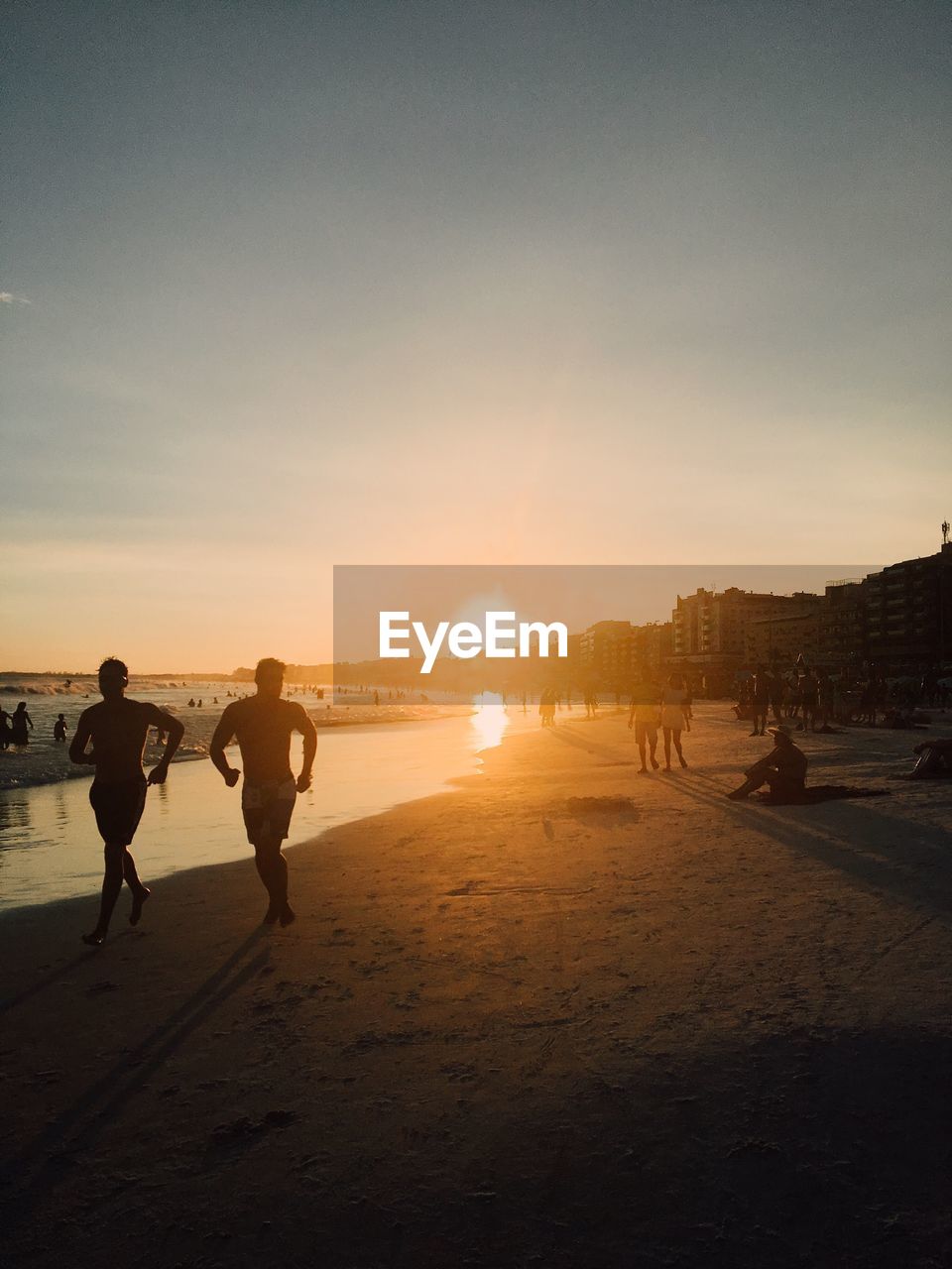 People at beach against sky during sunset