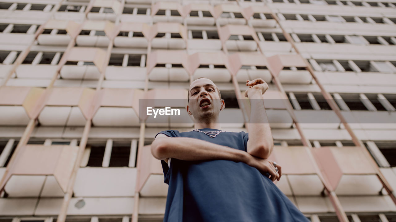 Low angle portrait of man standing against building in city 