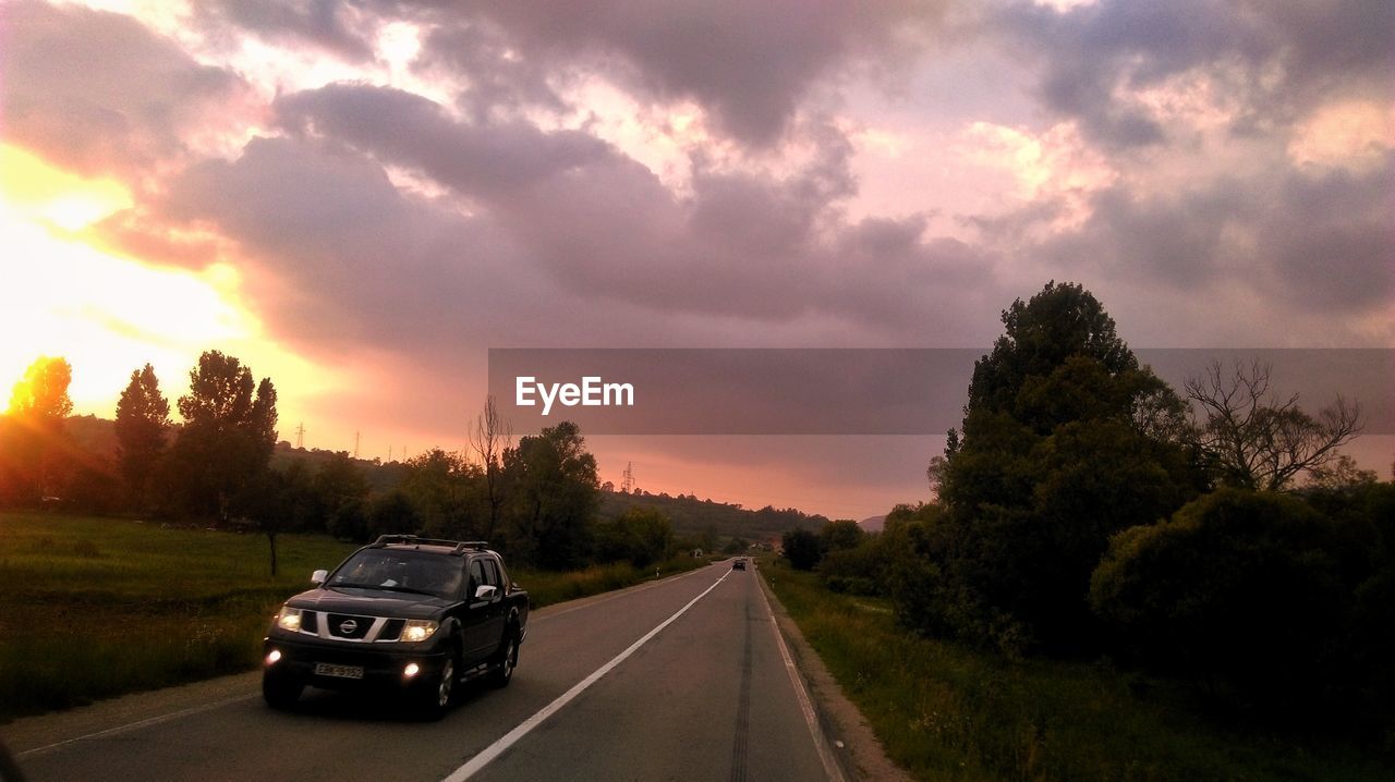 CAR ON ROAD AGAINST SKY