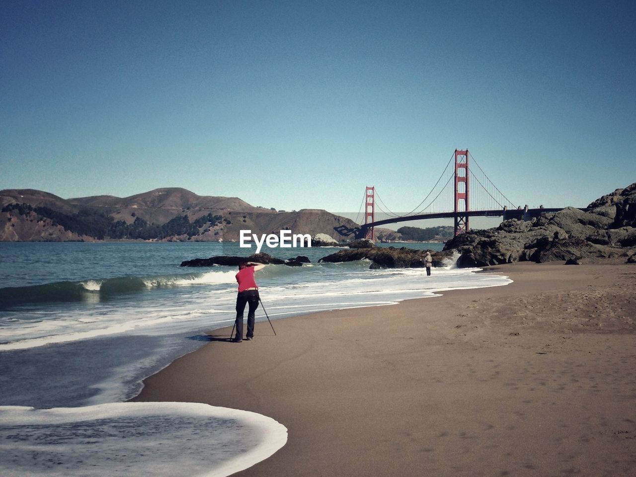 Photographer photographing golden gate bridge against clear blue sky