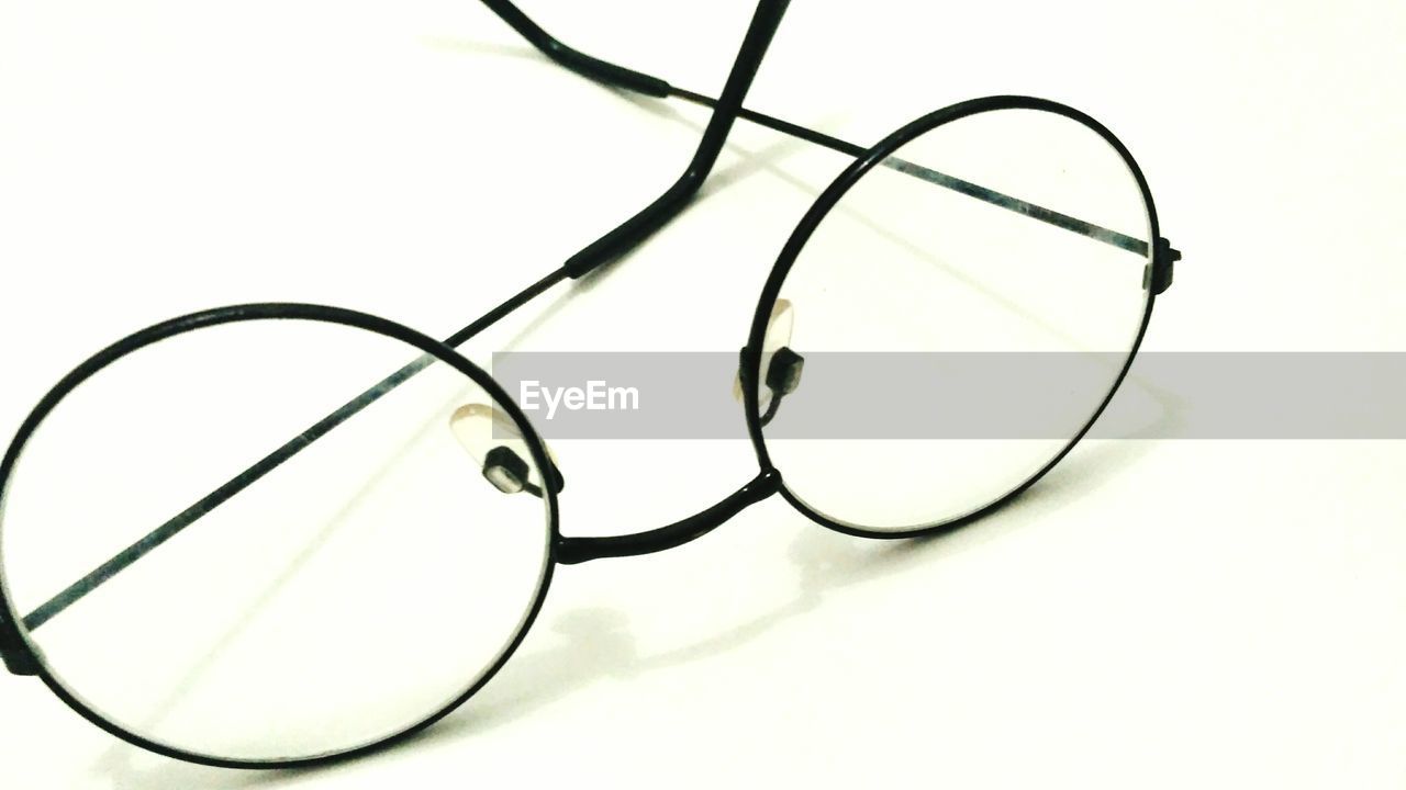 HIGH ANGLE VIEW OF EYEGLASSES ON TABLE AGAINST WHITE BACKGROUND