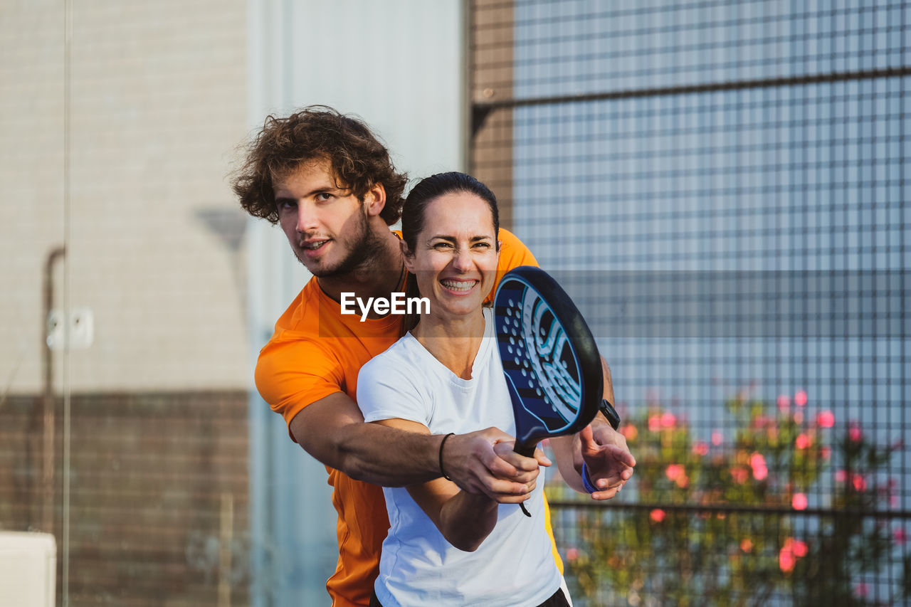 Portrait of smiling young man standing against wall