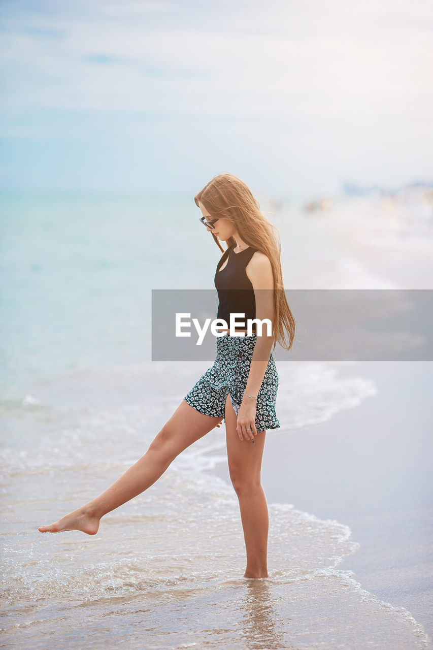 rear view of young woman standing at beach