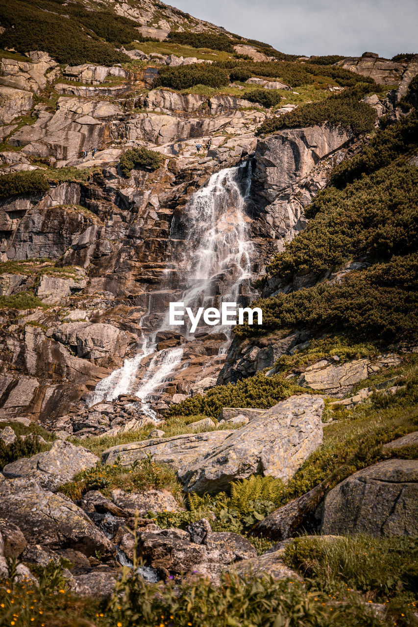 SCENIC VIEW OF WATERFALL ON ROCK FORMATION