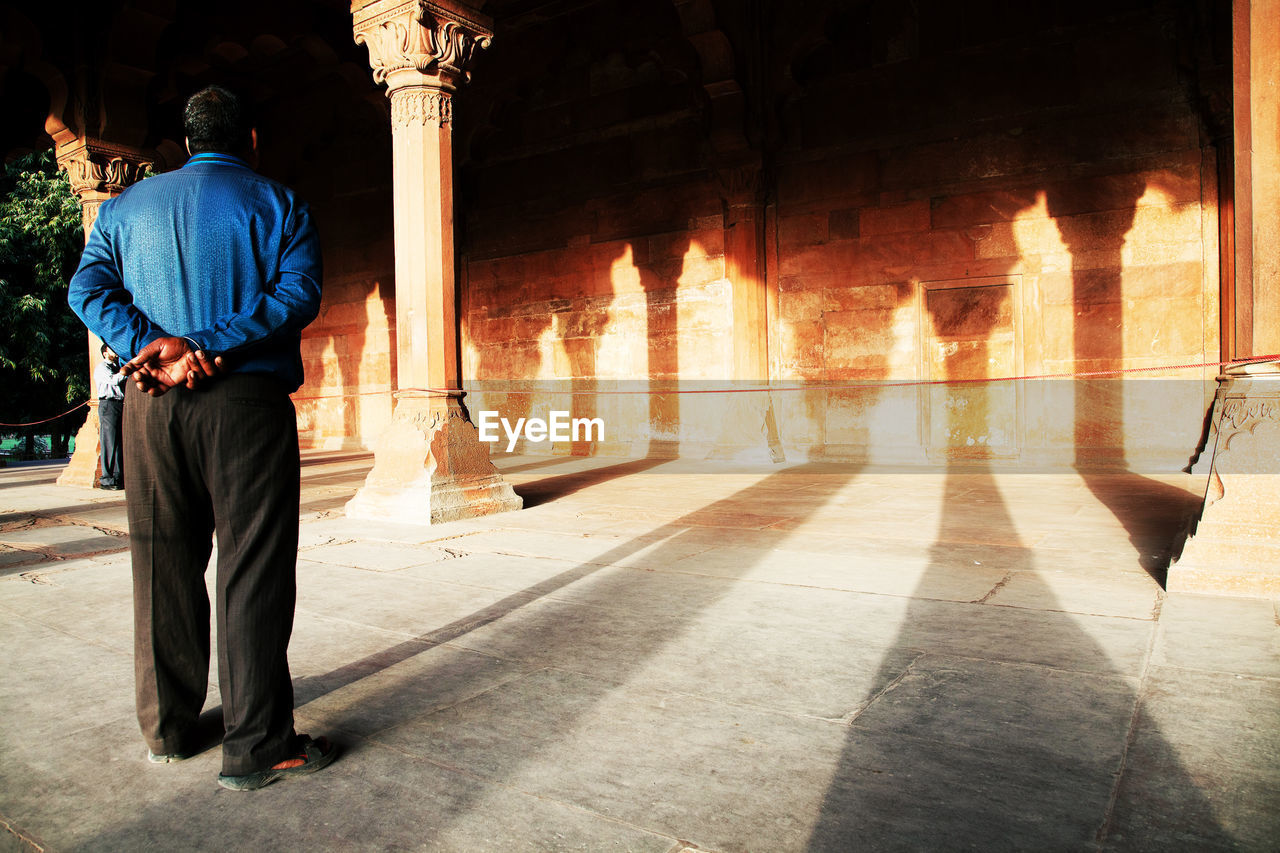 Full length rear view of man looking at red fort wall