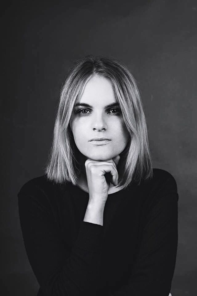 PORTRAIT OF YOUNG WOMAN LOOKING AWAY WHILE STANDING BY TREE