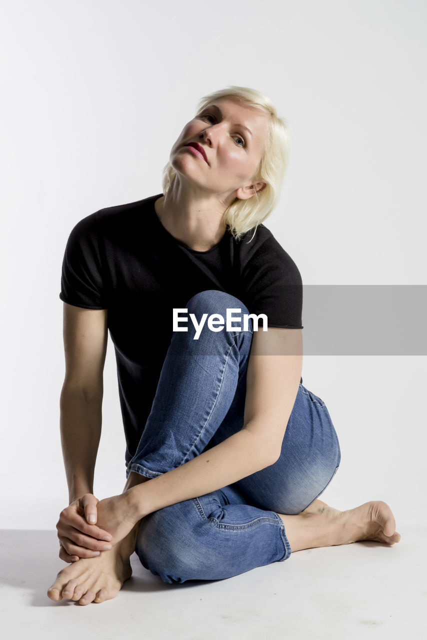 Portrait of woman sitting against white background