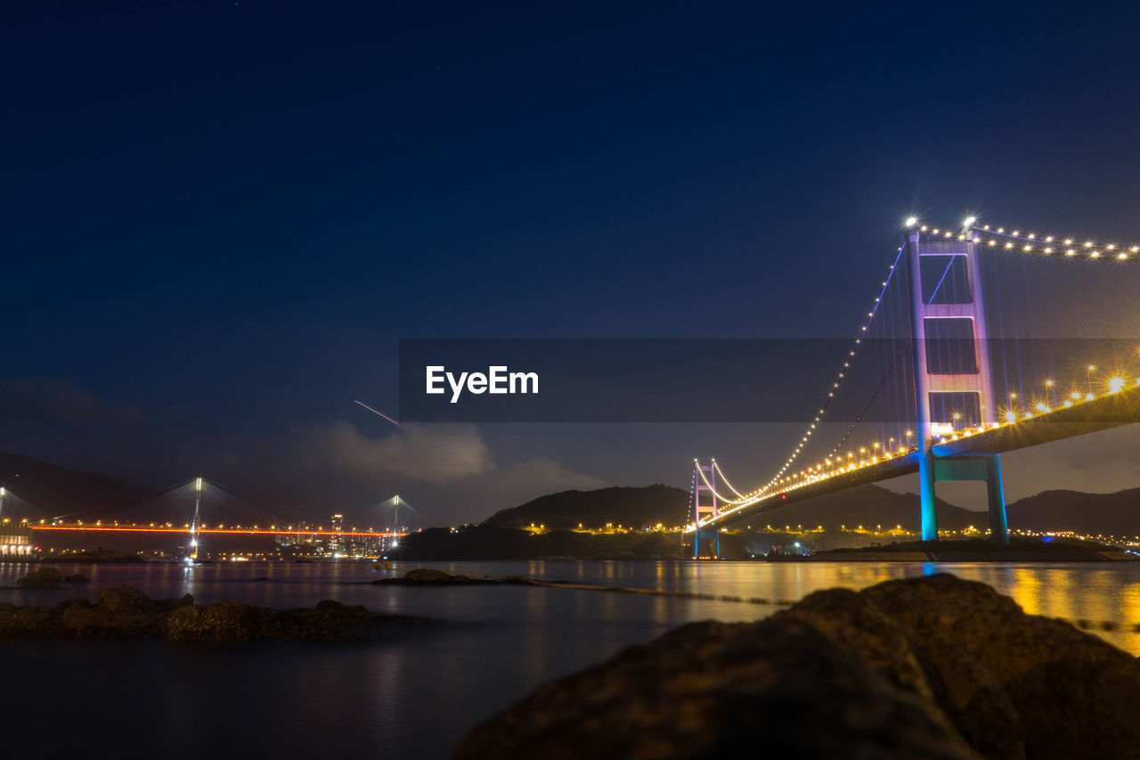 Illuminated bridge over river at night