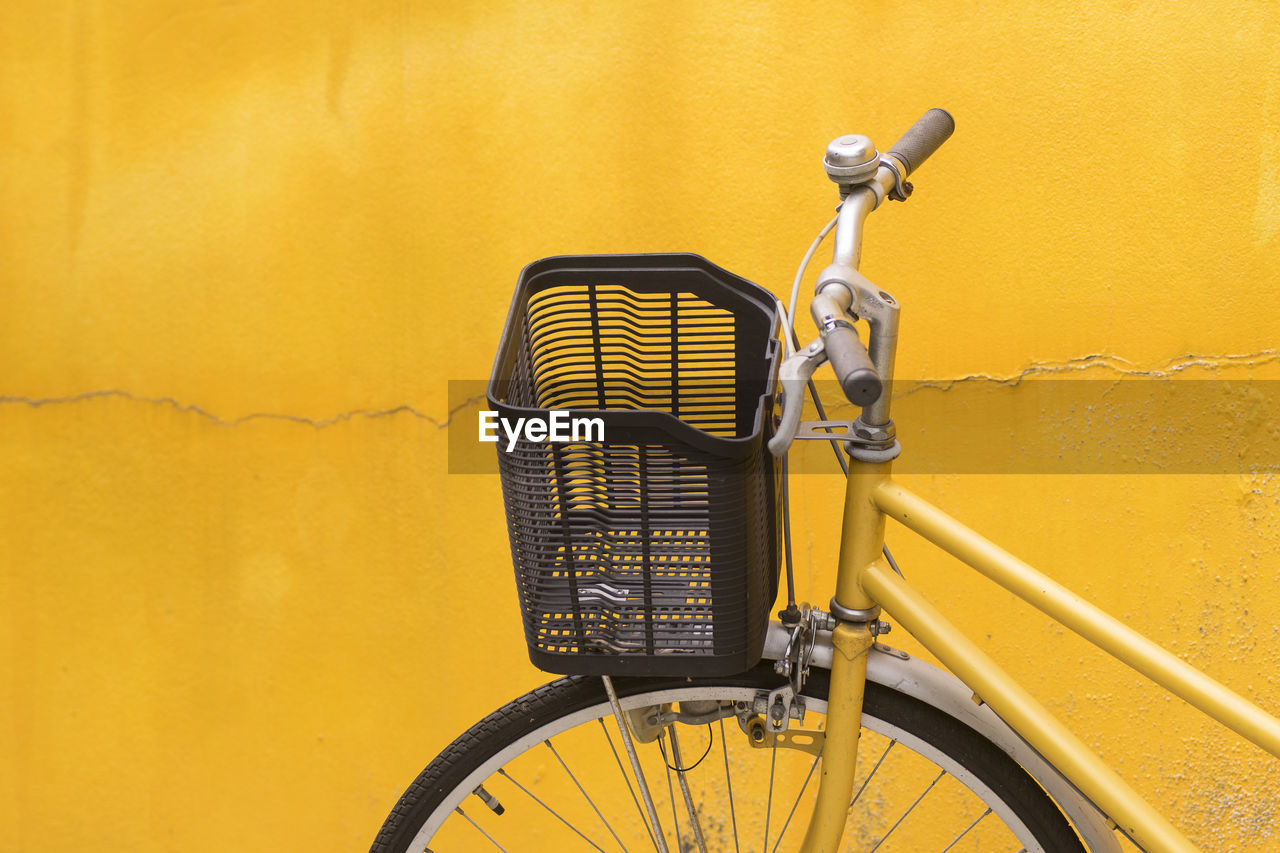 Close-up of bicycle parked against yellow wall