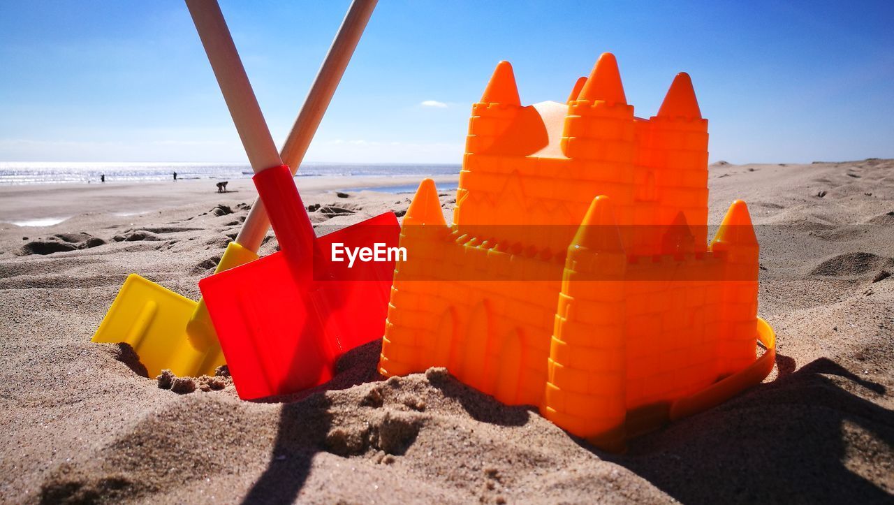 Close-up of plastic castle and shovels on beach