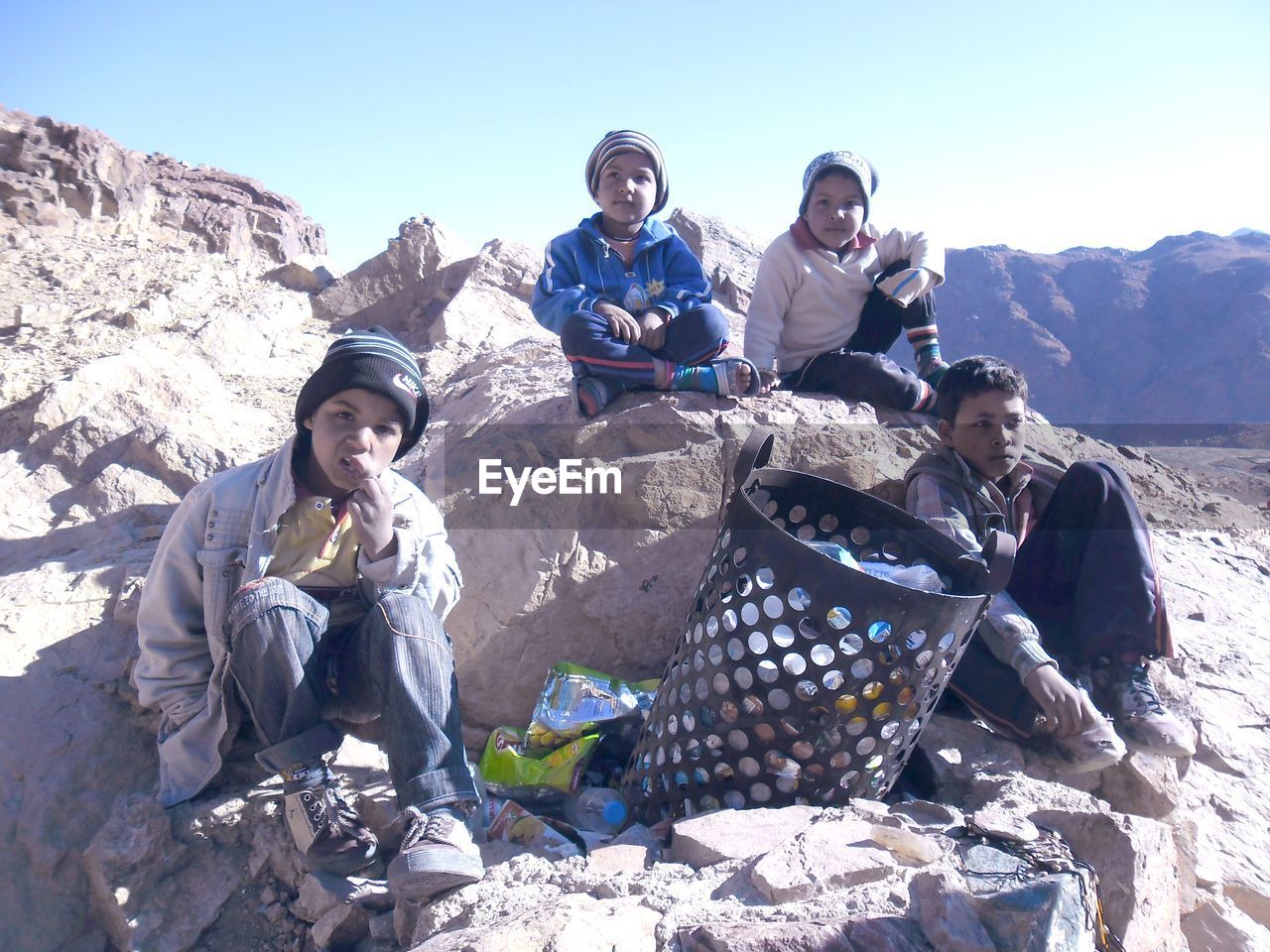 Friends sitting on rock formations amidst garbage can