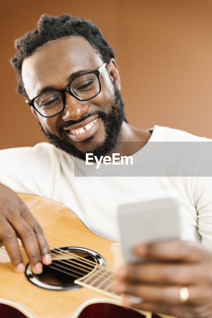 Smiling man using phone while sitting in studio