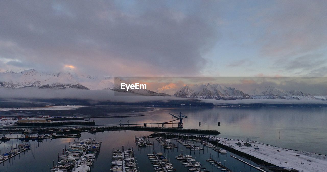 Aerial view of harbor against sky and mountains during sunset